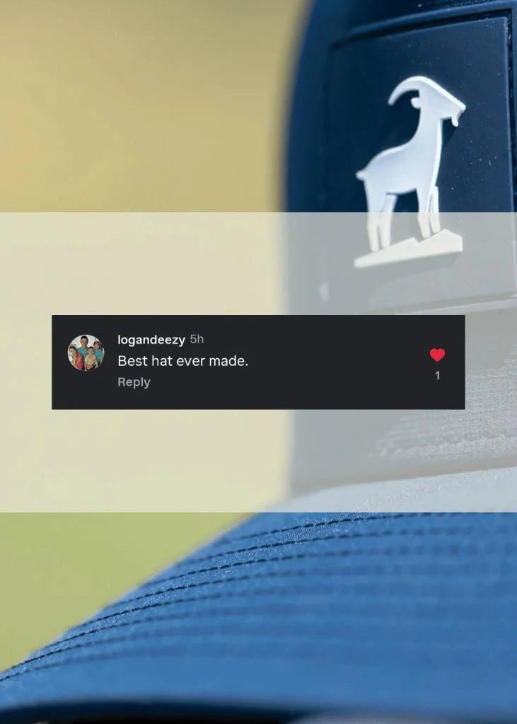 A close-up of a blue trucker-style cap with a white goat logo on the side, overlaid with a semi-transparent banner and a dark comment bubble. The background is a soft beige and green blurred outdoor setting.