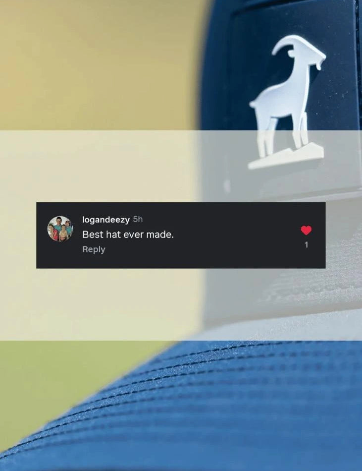 A close-up of a blue trucker-style cap with a white goat logo on the side, overlaid with a semi-transparent banner and a dark comment bubble. The background is a soft beige and green blurred outdoor setting.
